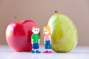 Toy girl and boy discuss nutrition and healthy choices in front of a green pear and a red apple. Concepts: nutrition good food choices balanced diet good for you